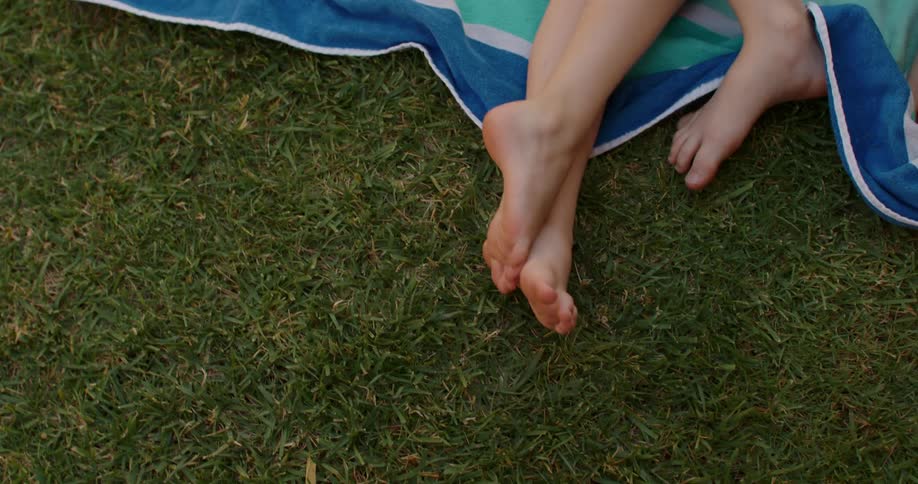 Children lie on large beach blanket on the lawn