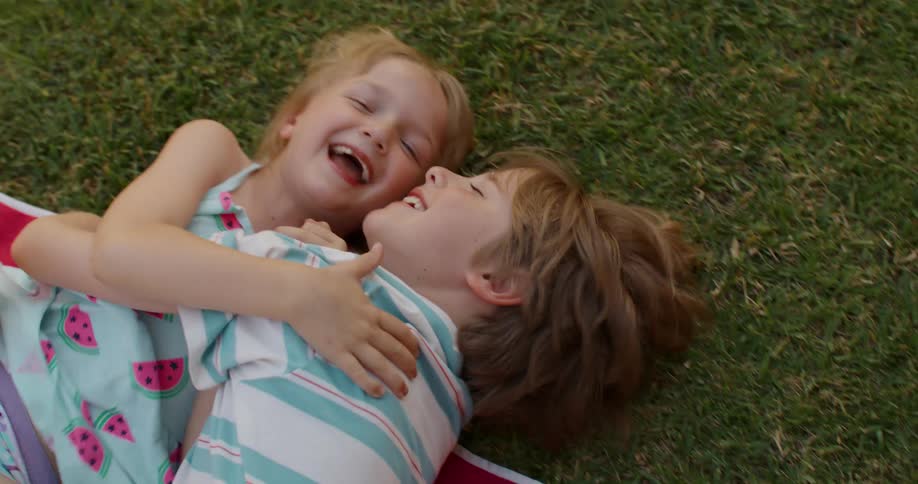 Two kids playing over a colorful blanket in the grass