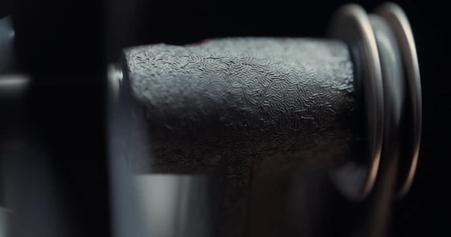 A closeup of a textured metal bar with spinning wheels and gears around it