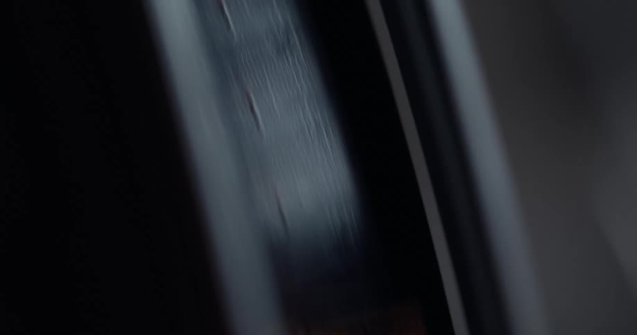 Dark metal strips running through a machine with raised sides