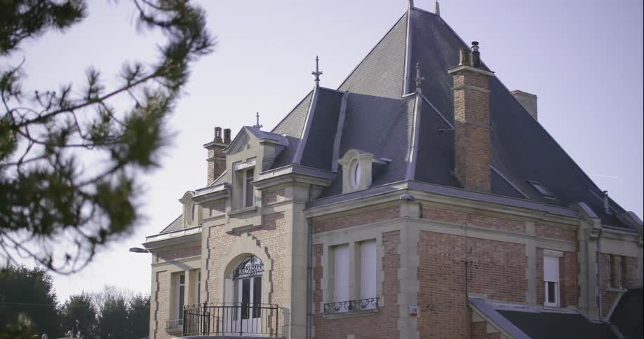 An old mansion stands against a blue sky in daylight