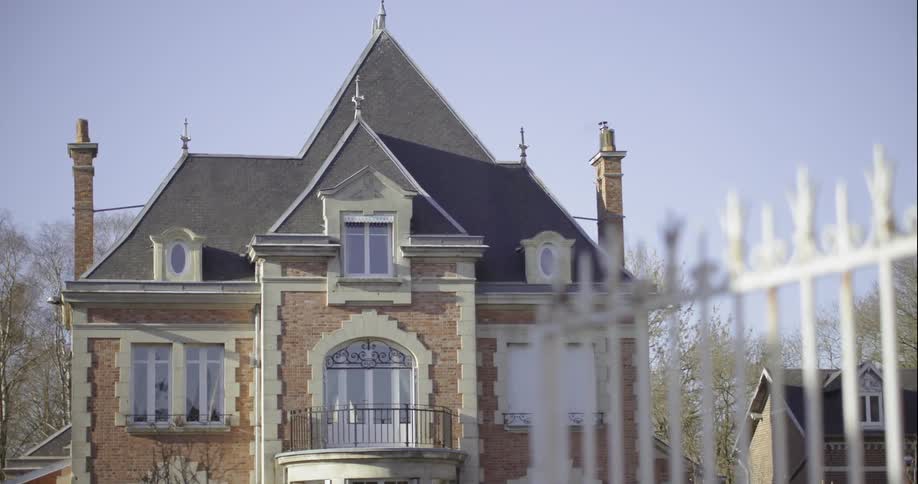 A gate is opening leading to an old mansion