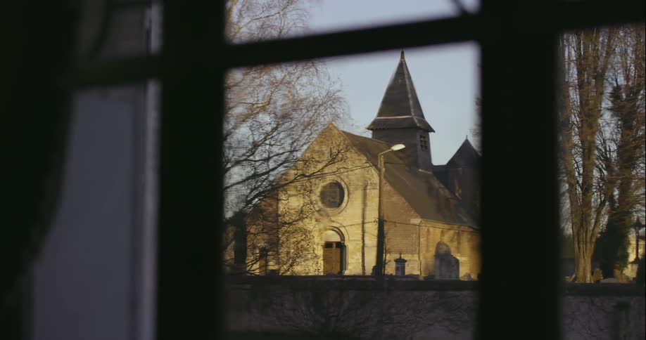 View of a building with a spire as seen through a local window
