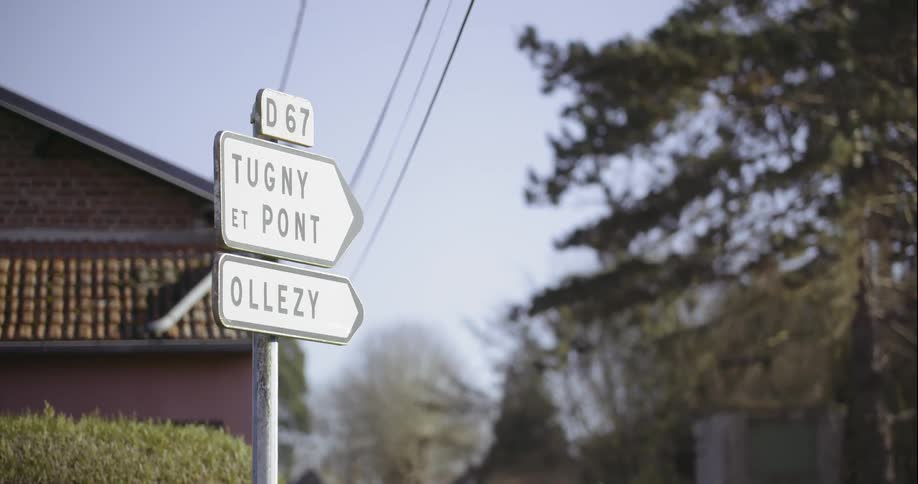 Street sign with a house and trees in the background