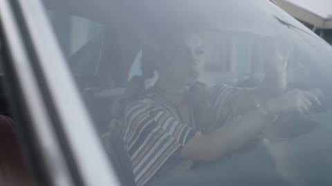 I woman sits in the driver's seat of a car