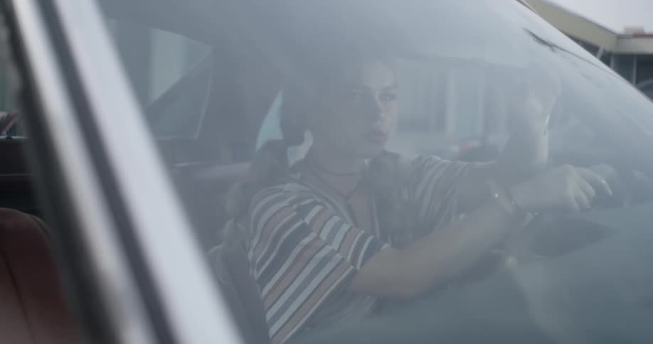 I woman sits in the driver's seat of a car