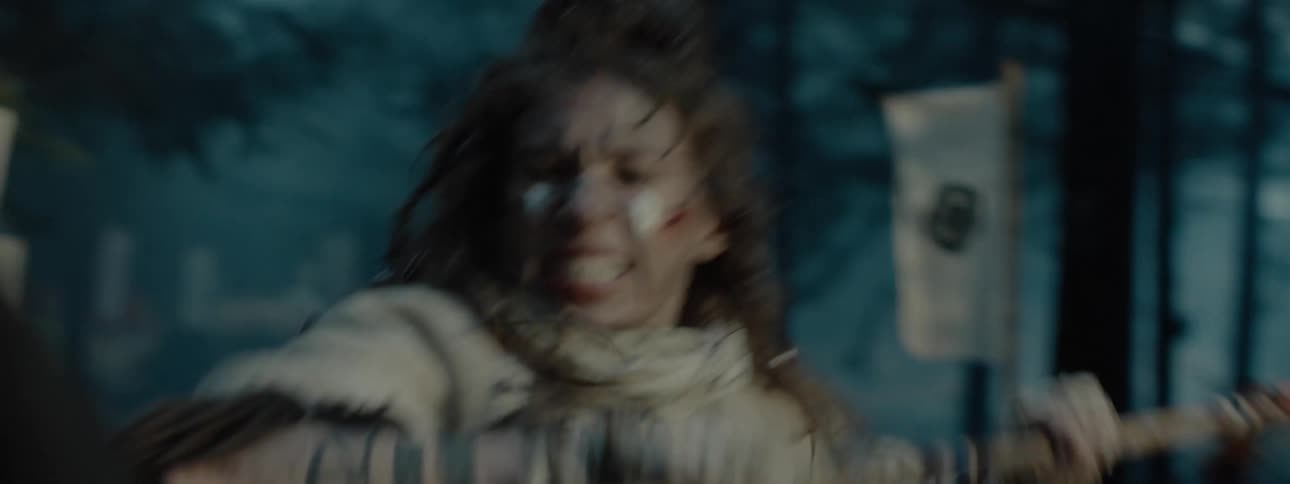 Woman dueling with a spear aggressively in the forest