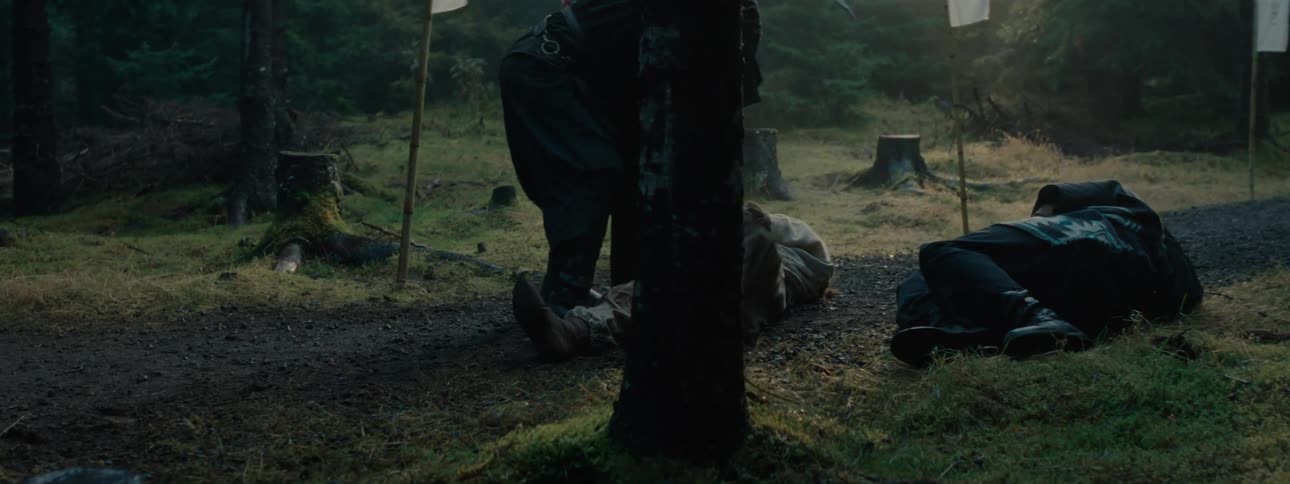A soldier stabs another soldier lying on the ground in the woods