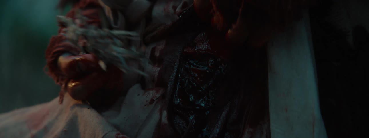 Pair of bloody hands placing twigs on belly wound