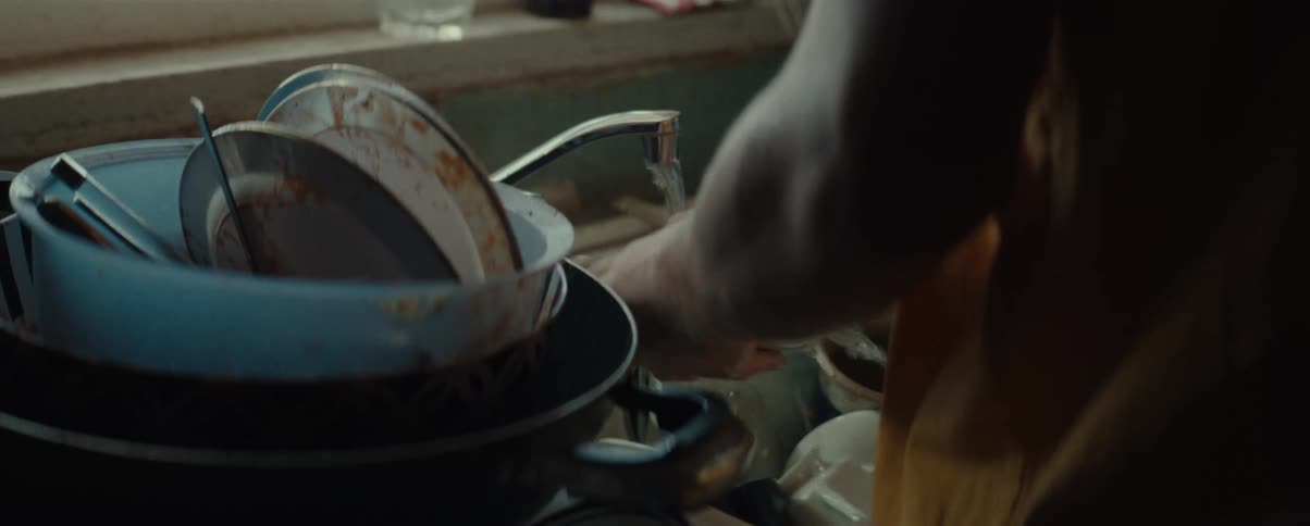 Closeup of a persons arm washing dishes in the sink