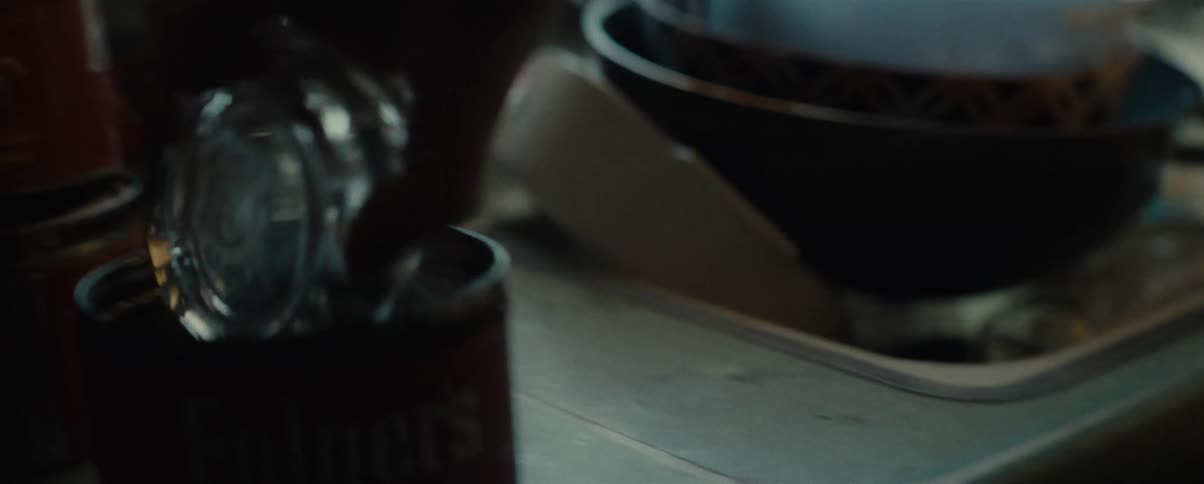 Man picks up glass ashtray and dumps it in a can on the counter near the sink