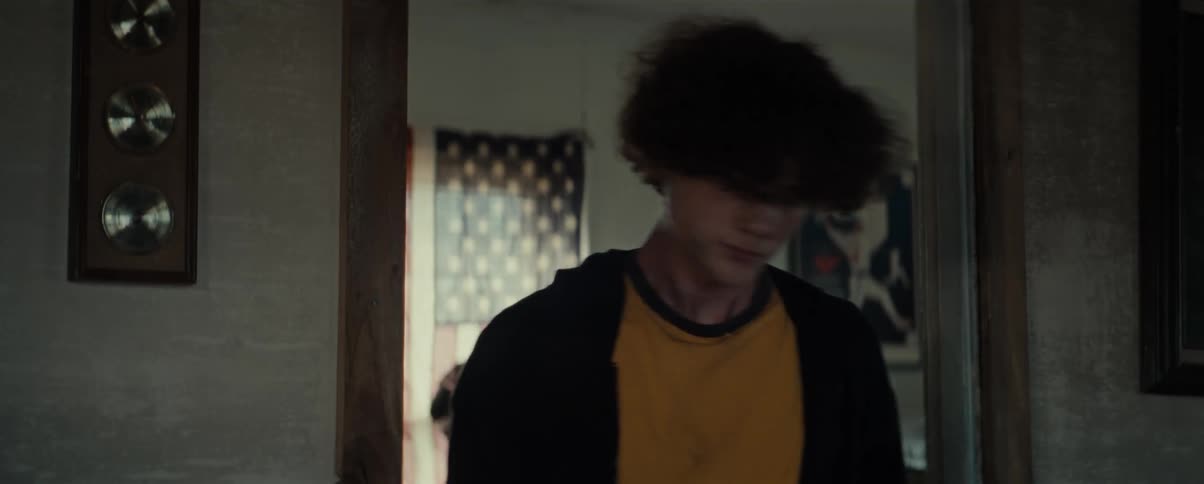 A young man walks through a doorway and leaves the room
