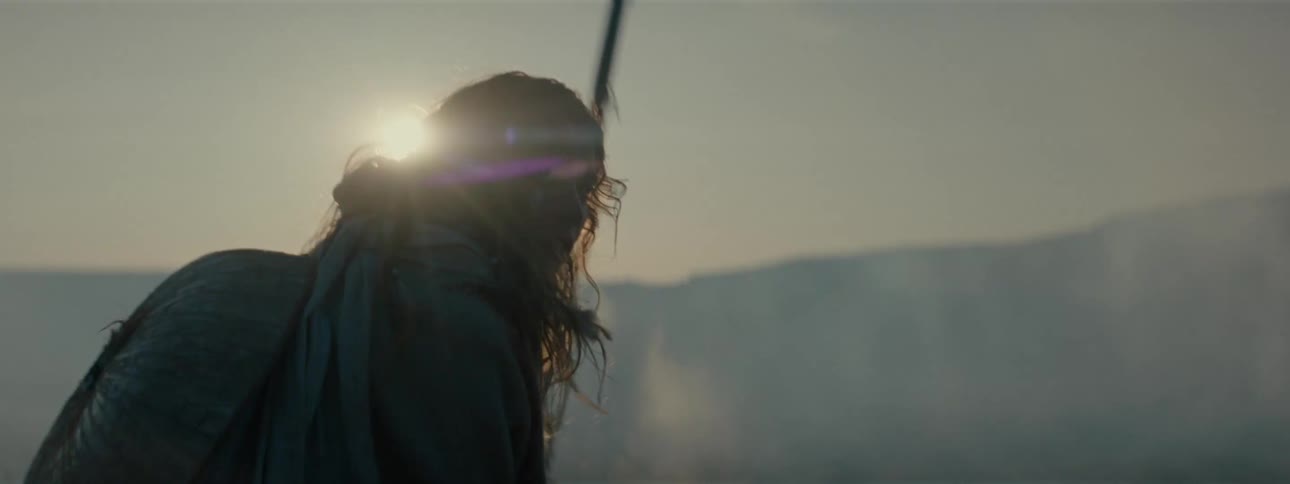 An exhausted soldier holding a spear keeps walking outdoors