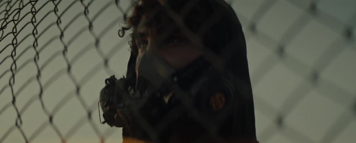 Portrait of a man in front of a fence wearing a futuristic mask