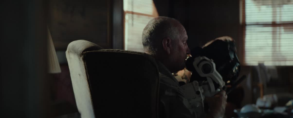 Man sitting in an armchair in the living room removing a mask