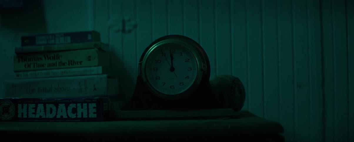 A clock is next to a stack of books