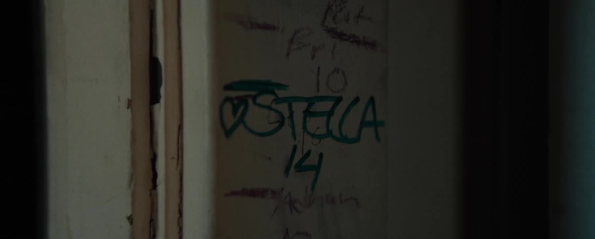 A weathered wall covered in graffiti and markings on a dimly lit room