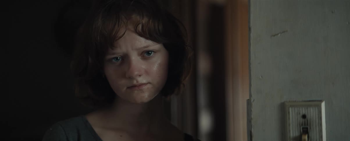 Young woman stands in hall frowning as she stares