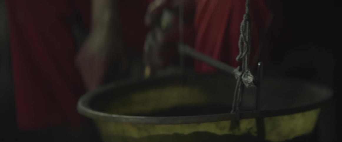 A woman stirring something that is in a hanging kettle
