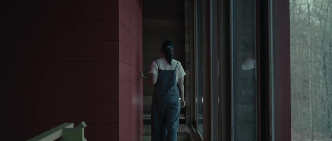 Woman walking in a hallway of a mirrored house located in a forest