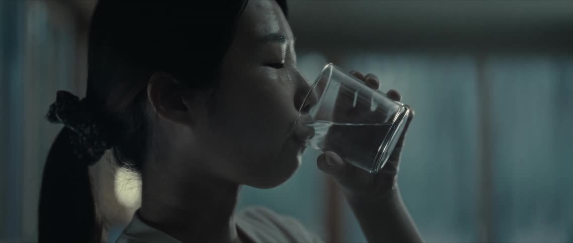 A woman with her eyes closed drinking water from a glass cup