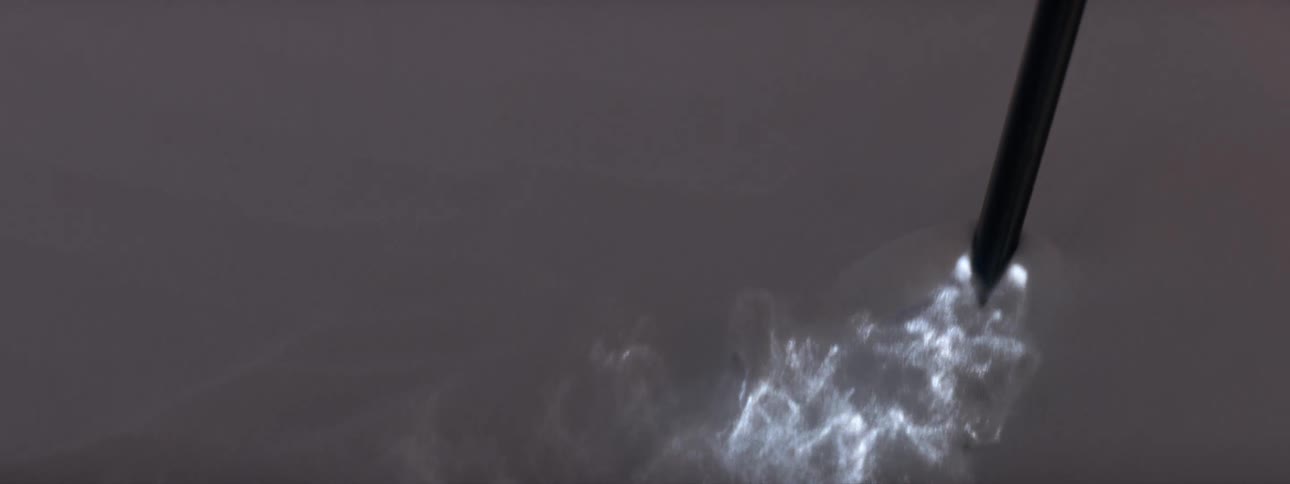 Close up of a pole or stick agitating the water surface leaving a bioluminescence wake behind