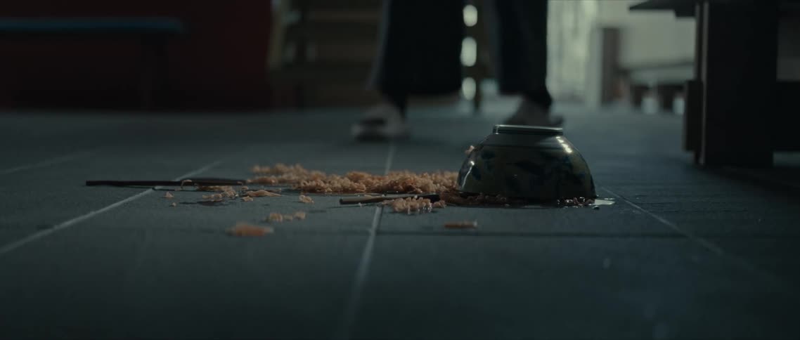A bowl with ramen fallen on the floor and a person approaches
