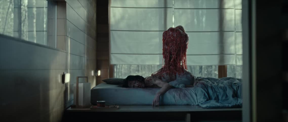 A horror scene of a mass of flesh rising from the back of a woman lying in a modern bedroom