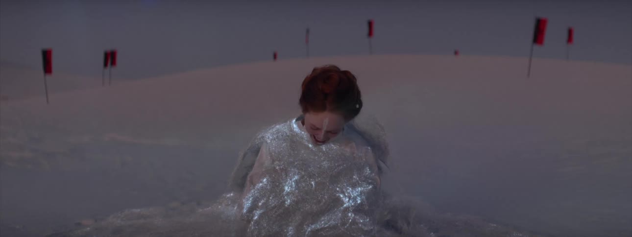 Woman stands resolutely before crying out in pain as she is enveloped by glowing liquid