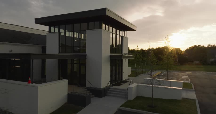Modern twostory building at dusk with large glass windows and an entrance with stairs