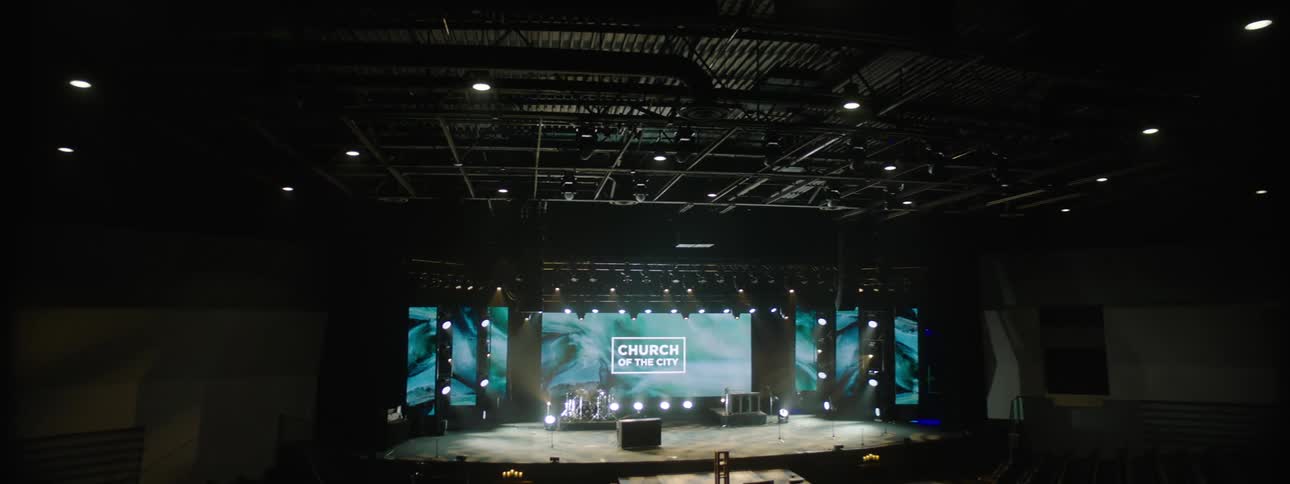 Interior architecture of an auditorium with a lit stage and a screen