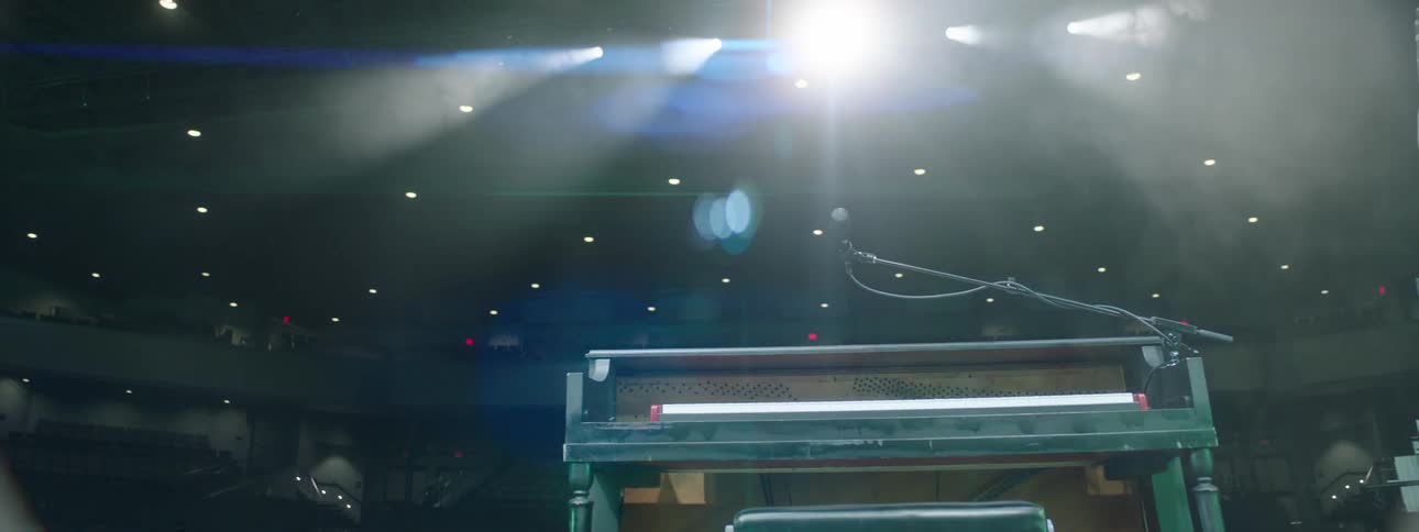 Piano on a stage lit with a bright spotlight in an atmospheric setting
