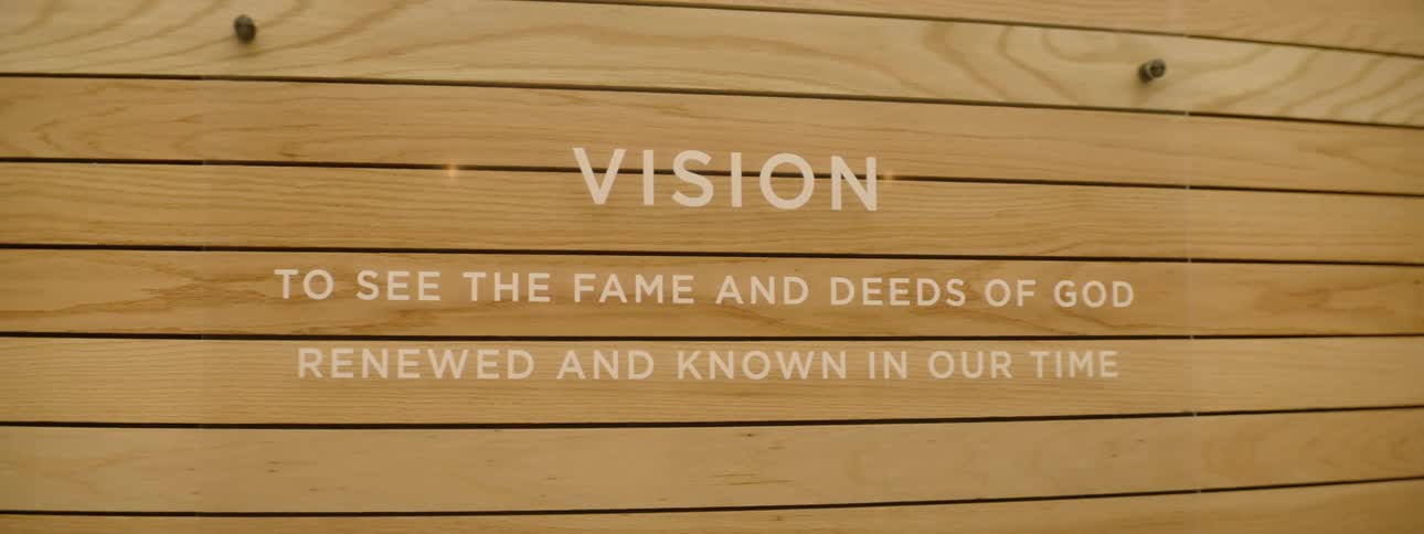 Light wooden plank wall with a glass plate with white text