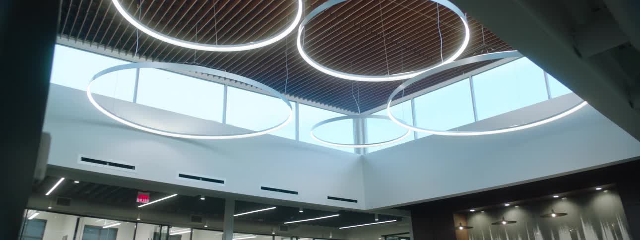 Large simple circular lighting fixtures hang over a meeting area in an office building