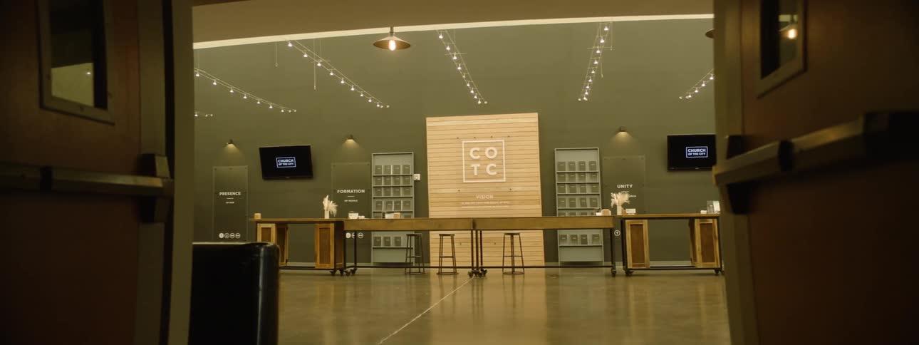 A modern coffee shop interior with a large wooden counter menu boards and string lights hanging from the ceiling