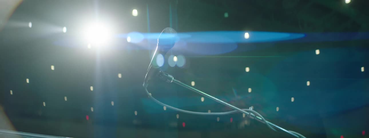 A microphone on a stand under a spotlight in a theatre