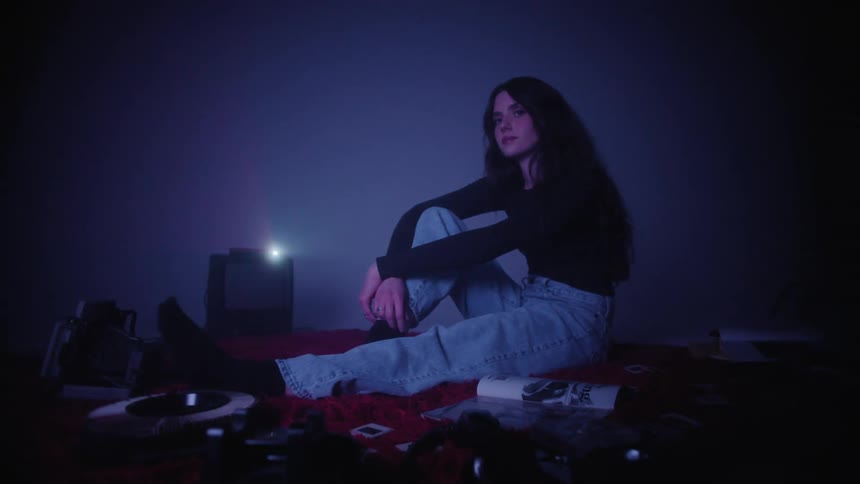 A woman sits by a machine that is flashing light