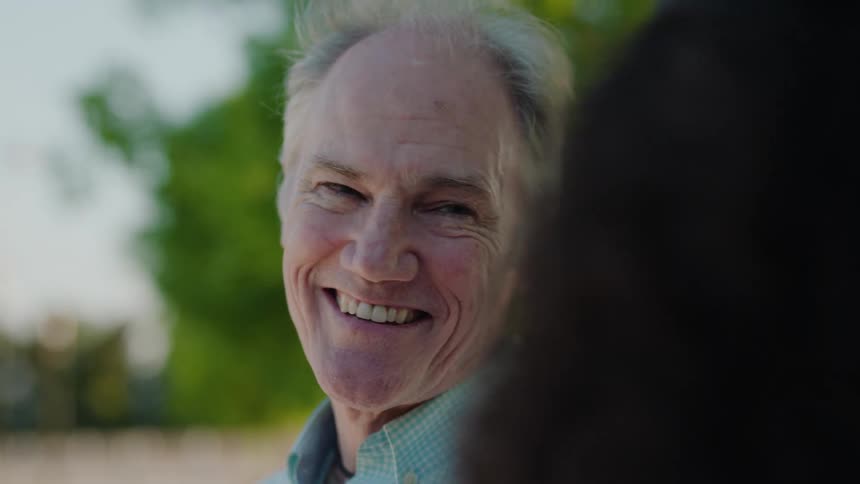 Older man smiling while listening to a younger woman talking