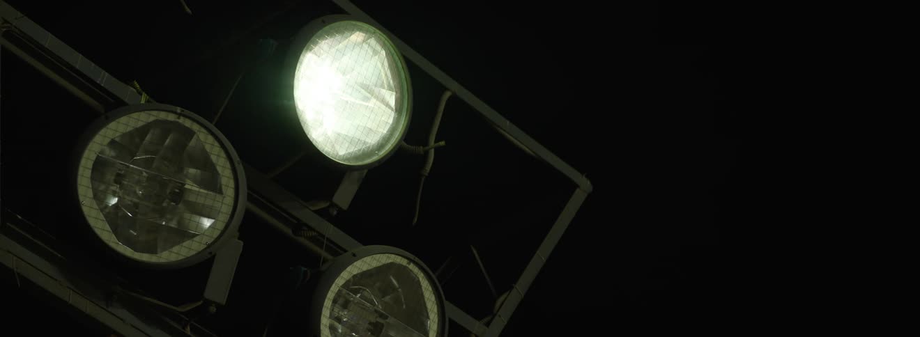 Three studio spotlights on a dark background lighting up