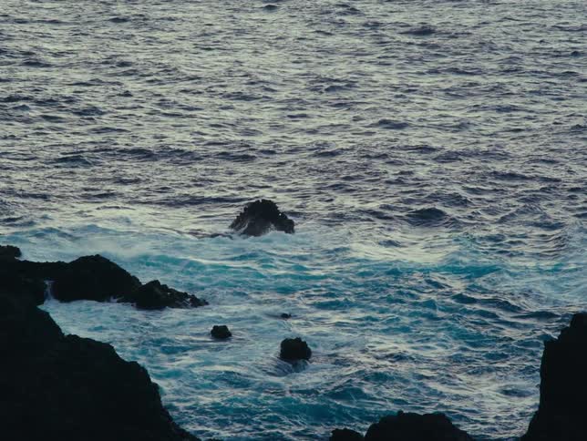 Large waves wash ashore against a rocky coastline