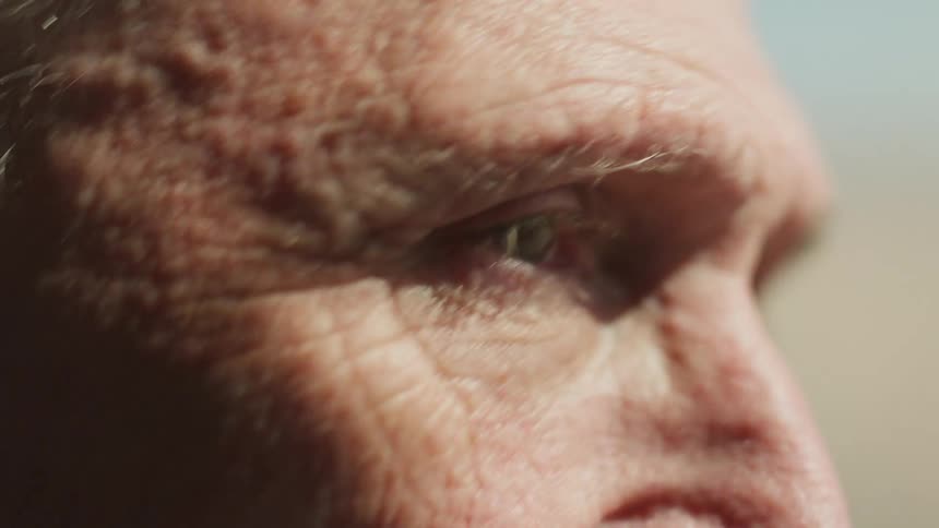 Old man visible only from the nose up bouncing up and down with the sky speeding by behind him