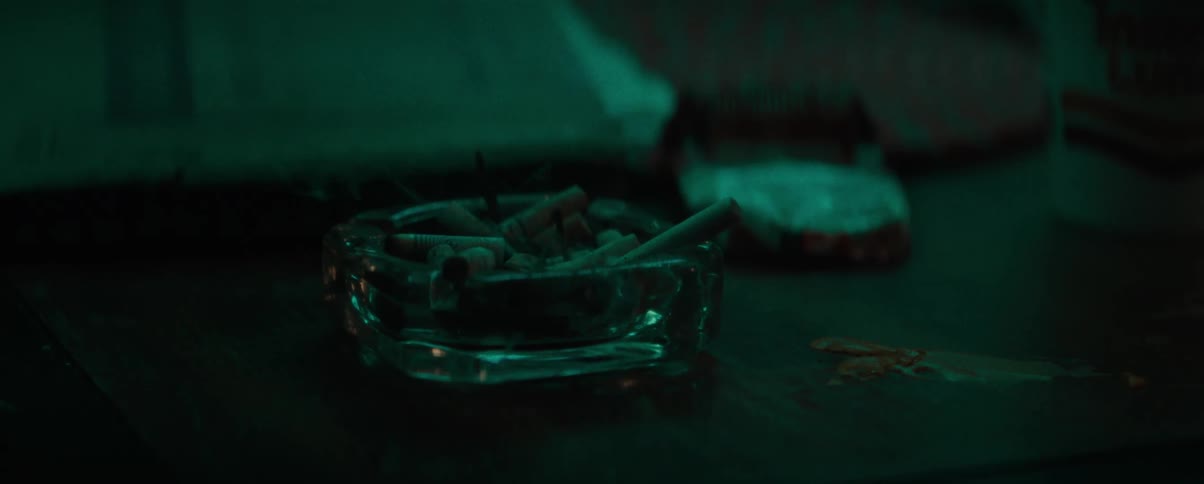 Glass ashtray full of cigarette butts on a dark wooden surface
