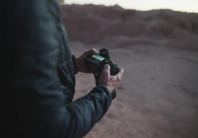 A photographer looks at the pictures on a dslr camera screen display while taking pictures of the desert