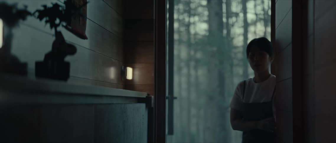 A woman entering a door that is open in a room with a wooden wall