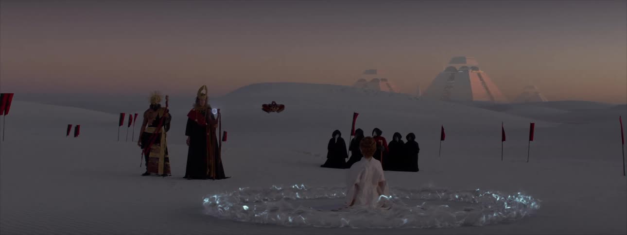 Some people in a desert and there is one of them sitting and blue lights are circling her