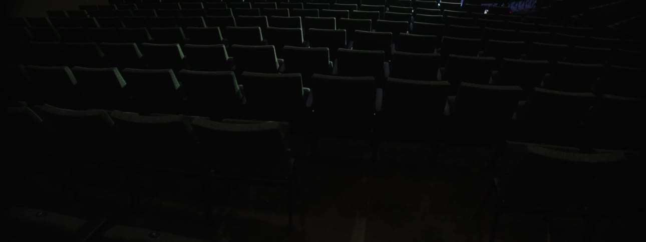 Organized chairs and lights in the background inside an auditorium