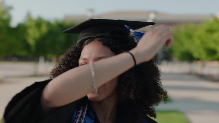 Happy graduate moving her tassel from right to left side of cap