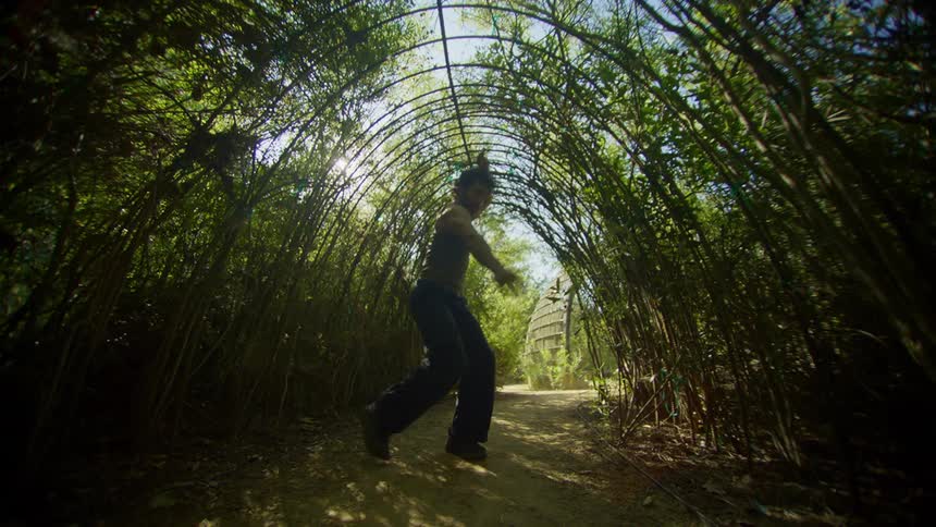 Man in nature inside an arch with trees around dancing
