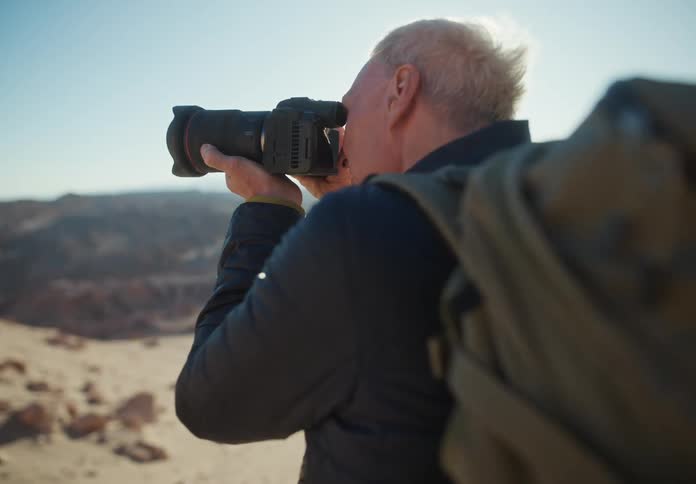Man with a backpack on his back and a professional camera photographing a natural environment