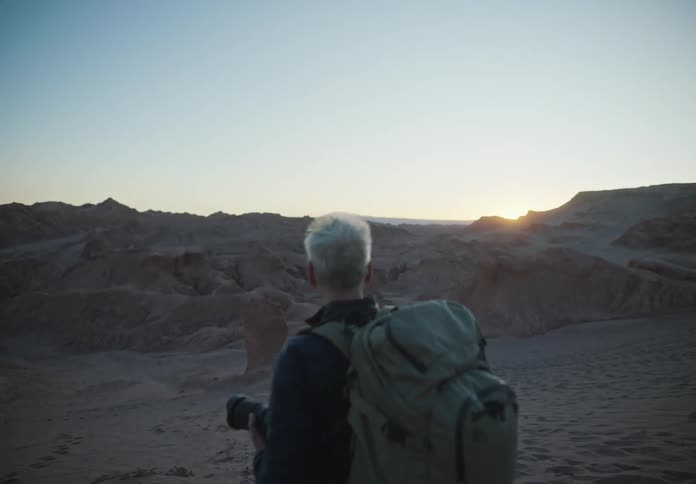 Man with a professional camera photographing a sunset sky in a desert environment
